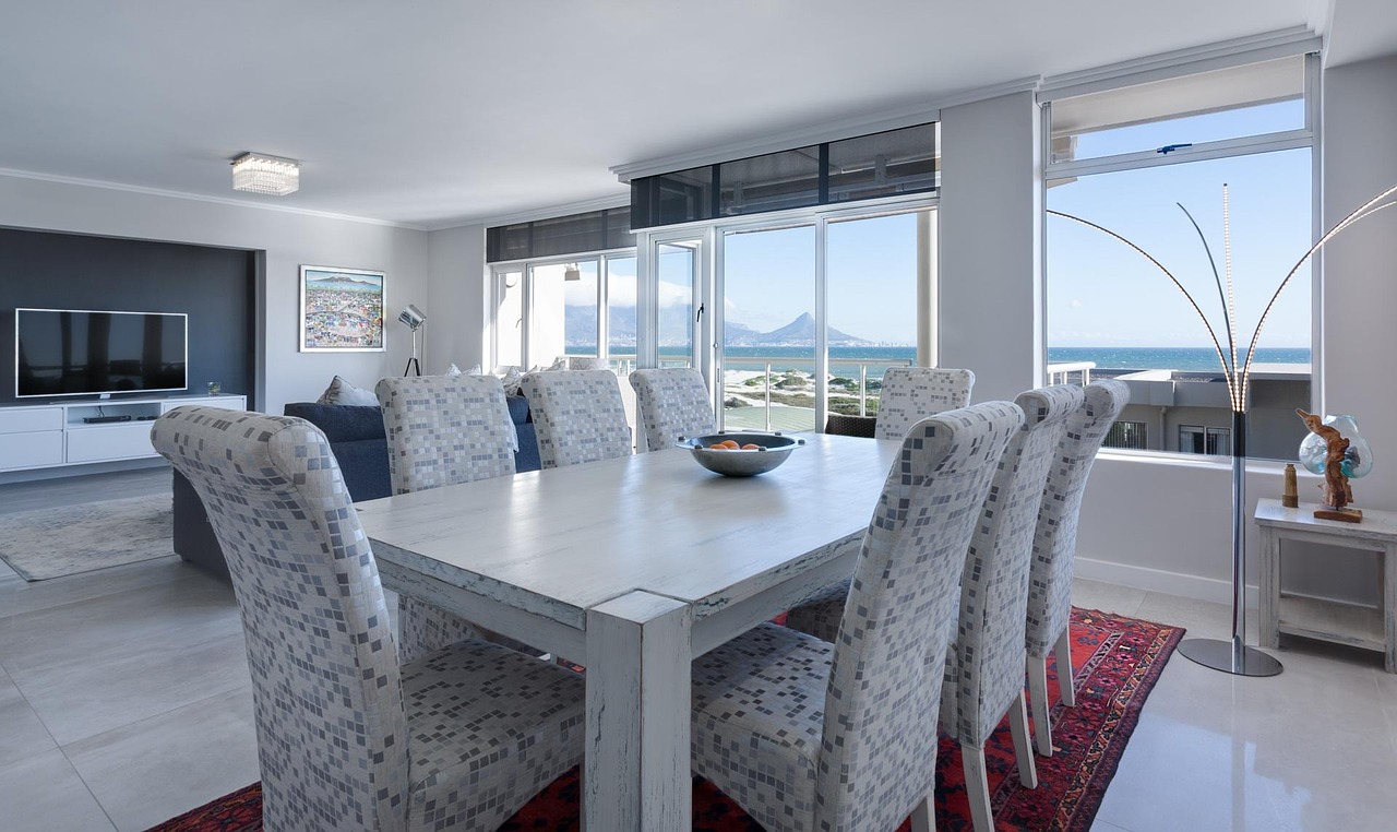 A bright dining room whose tall windows look out to the sea